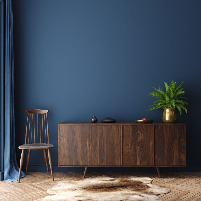 Amenajare living stil minimalist - perete bleumarin, scaun din lemn, comoda din lemn cu 4 compartimente, covor animal print, vaza aurie cu planta