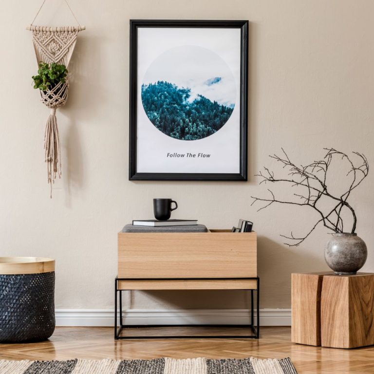 Amenajare living stil minimalist - perete crem, tablou cu padure in cerc, vaza cu crengi, cub din lemn, decoratiune suspendata pentru plante