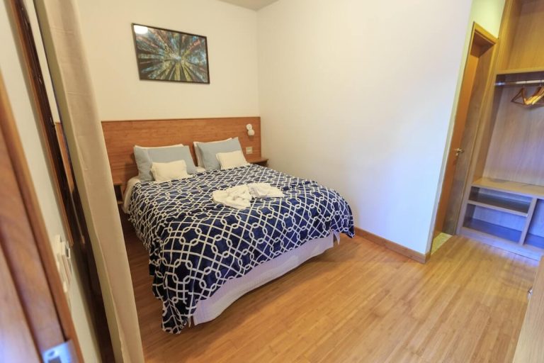 2.-Amenajare-dormitor-pat-dublu-asternuturi-albastru-cu-alb-cu-model-tablie-pat-din-lemn-maro-tablou-parchet-maro.jpg